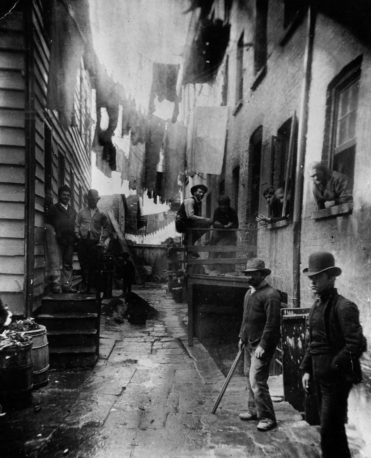 A group of men loiter in an alley off Mulberry Street known as "Bandits' Roost." 1888
