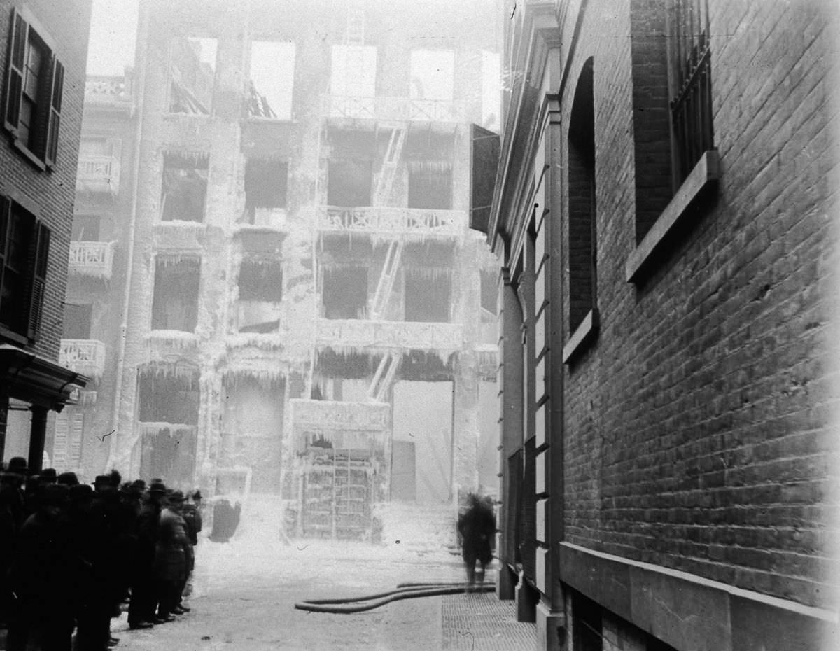 A crowd stands in front of the frozen facade of a burned building on Crosby Street at Jersey Street, 1896