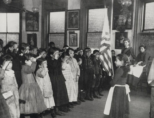 Immigrant children saluting the flag in the Mott Street Industrial School