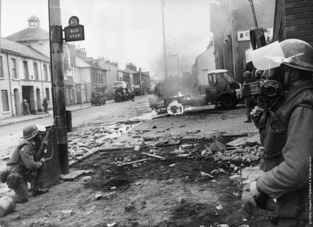 Armed British troops take up defensive positions on the Falls Road, 4th July 1970. 5 Catholics were killed, 60 injured and many homes devastated when the British Army imposed a curfew in the Falls Road.