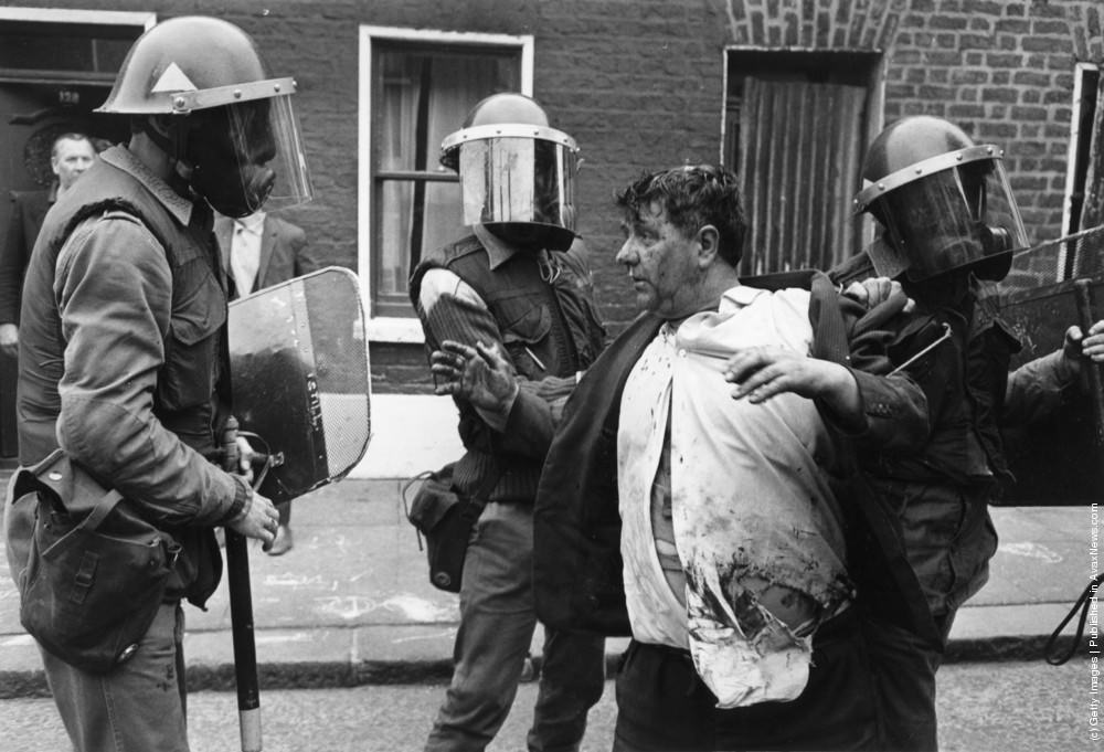 Armed British soldiers restrain a young civilian in the streets of Belfast, 3rd July 1970.