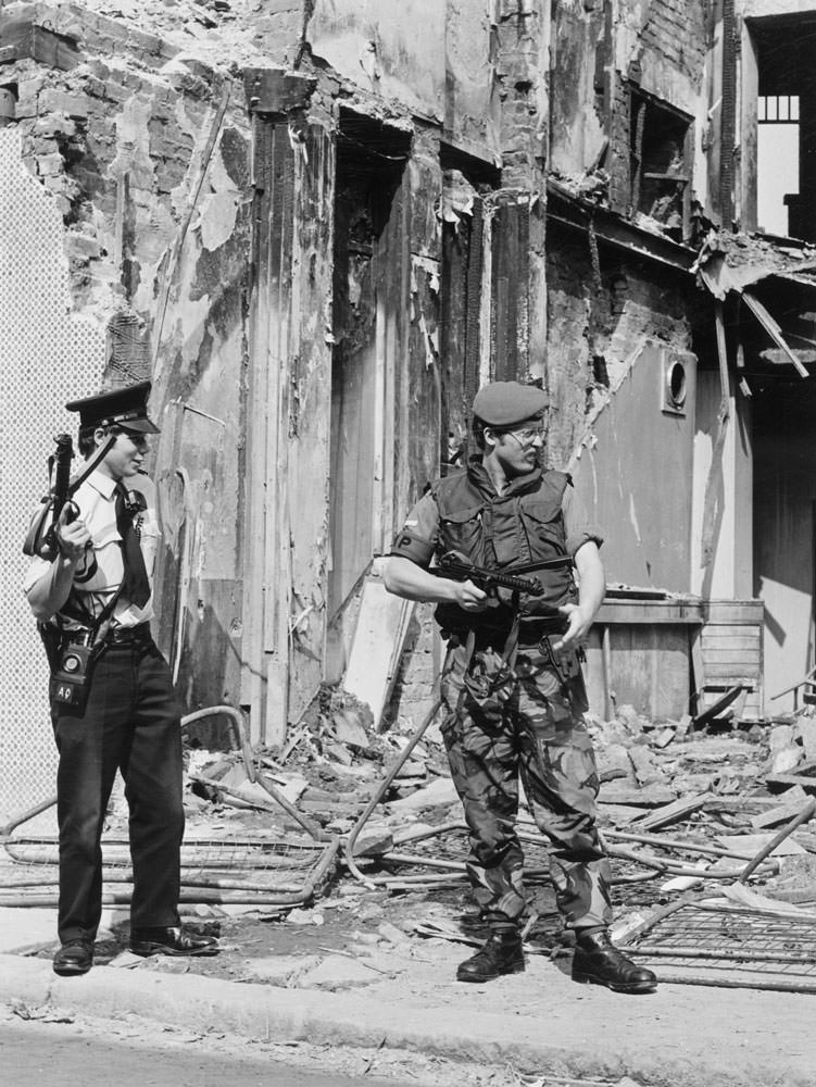 An RUC officer and Royal Military Policeman stand guard by a bombed building, 1979.