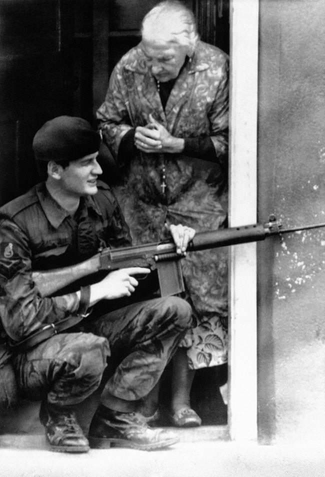 An old woman, a rosary dangling from her neck, clasps her hands on finding a British Army sharpshooter on her door step in BelfastÂs market area as troops flushed out snipers barricaded in bakery in Northern Ireland capital on August 11, 1971.