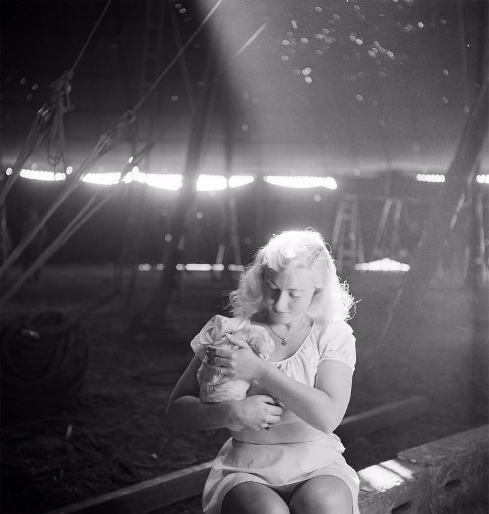 A picture of a circus girl sitting and holding a dog during a rehearsal for the Ringling Bros. and Barnum & Bailey Circus in Sarasota, FL in 1949.