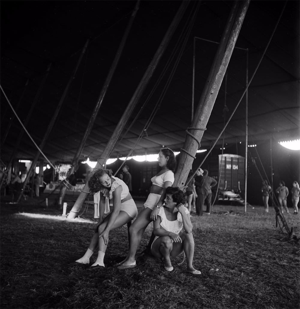 Three circus girls relaxing near a pole during a rehearsal for the Ringling Bros. and Barnum & Bailey Circus in Sarasota, FL in 1949.