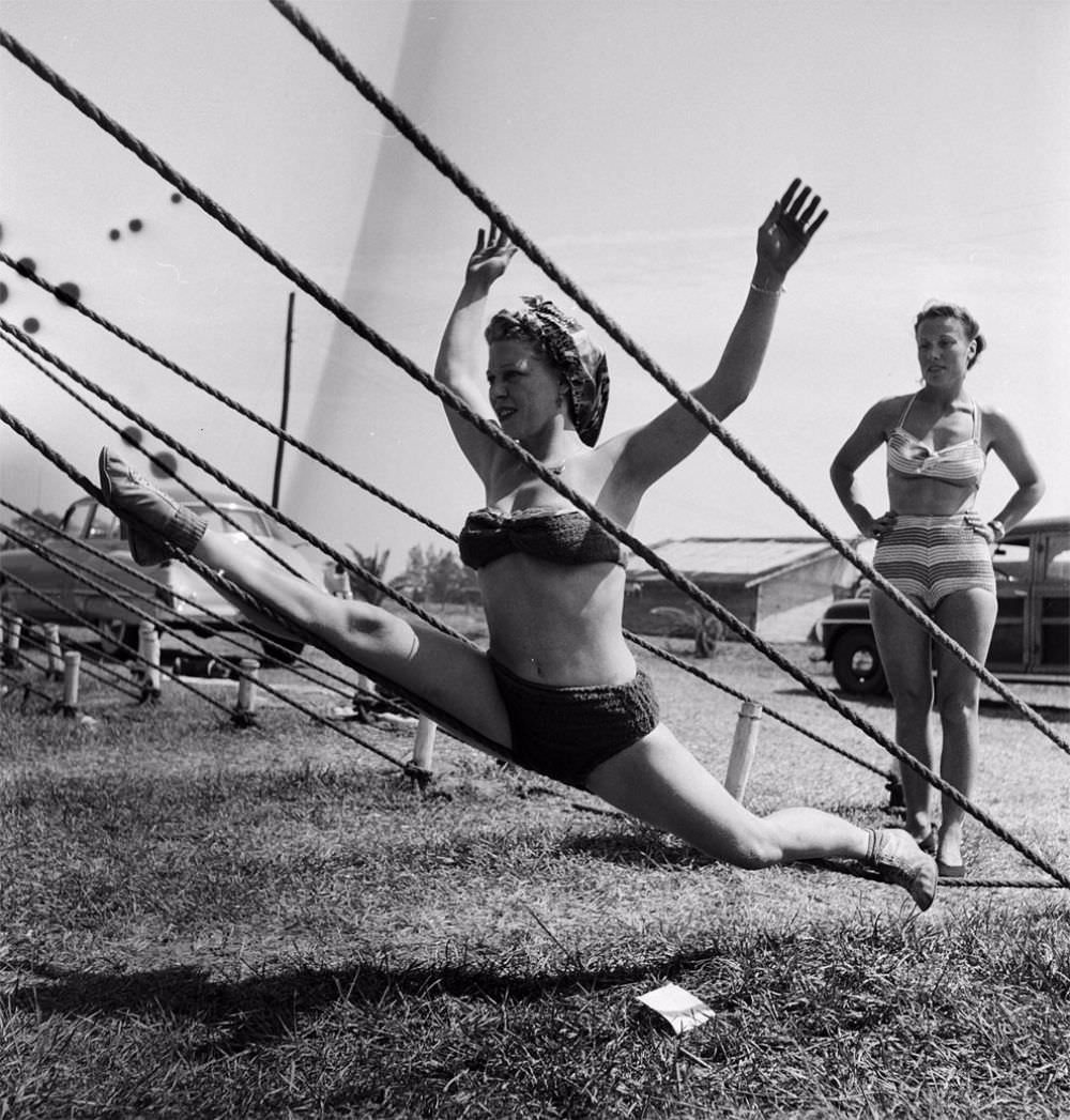 An acrobat practicing on a tent rope while an unidentified woman is standing nearby during a rehearsal for the Ringling Bros. and Barnum & Bailey Circus in Sarasota, FL in 1949.