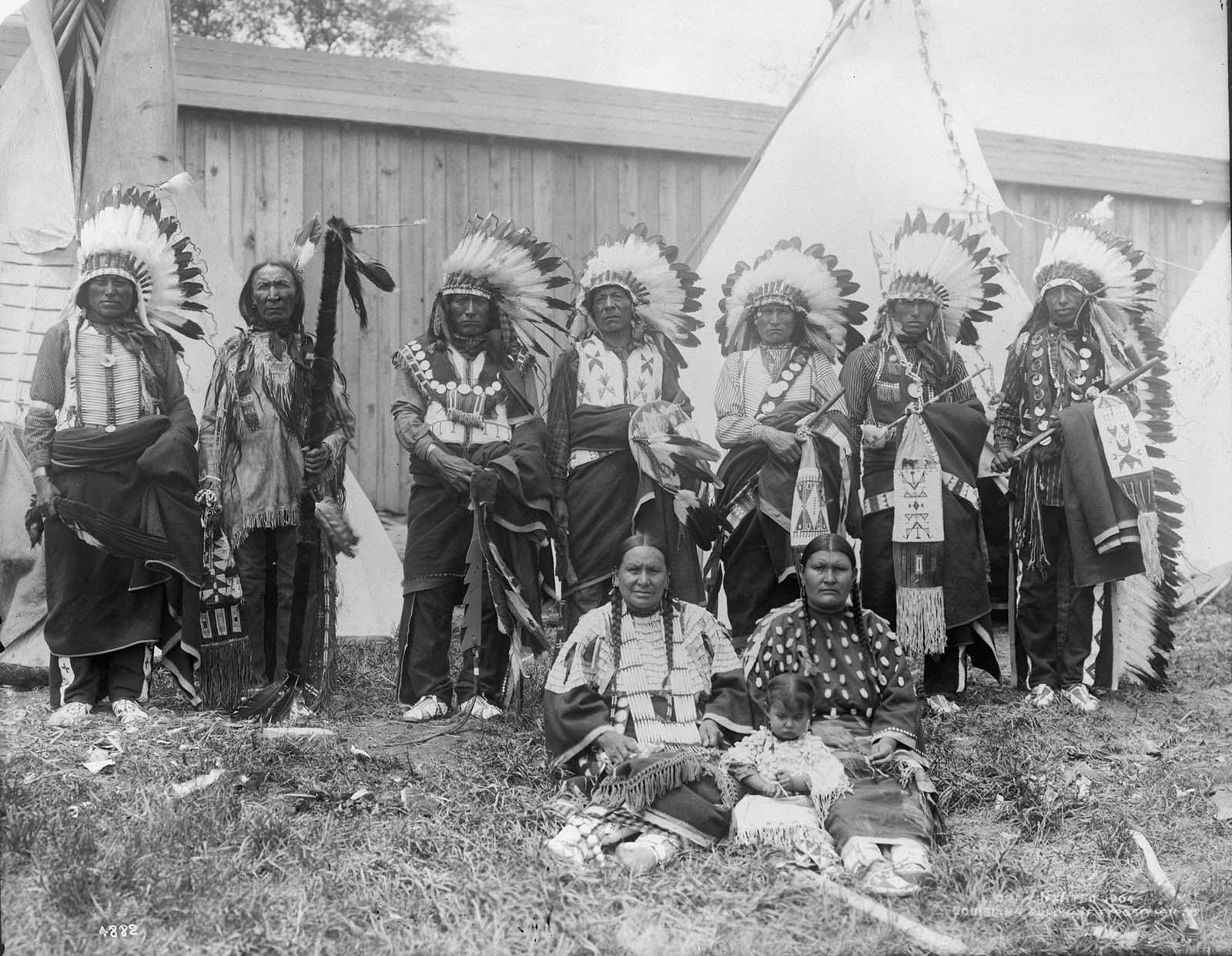 Chief Yellow Hair and his council standing in front of replicas of teepees at a human zoo at the 1904 World’s Fair in St Louis, Missouri.