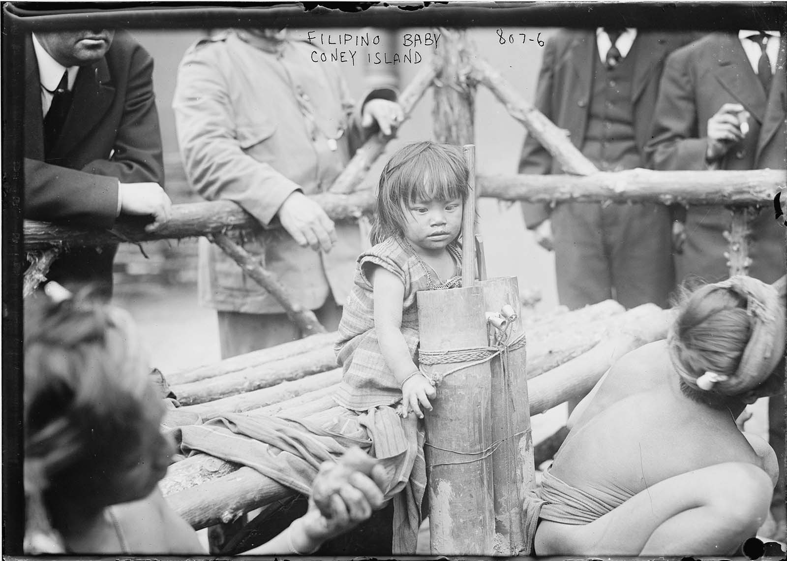 A young Filipino girl sitting on a wooden bench in an enclosure in Coney Island, New York in another horrifying 1906 ‘exhibit’.