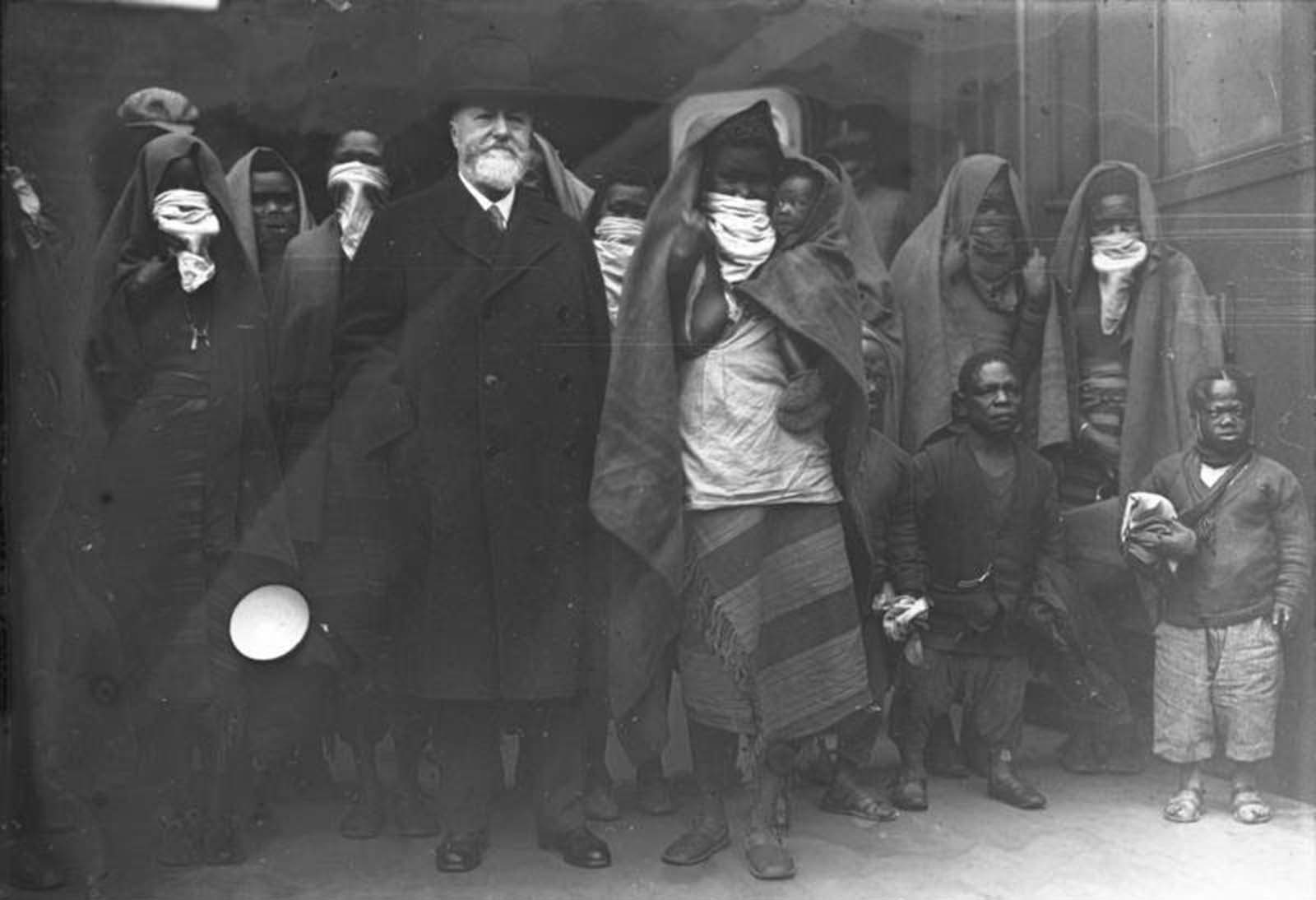 Professor Lutz Heck, director of the Berlin Zoo, arrives in Berlin, 1931. With him are members of the African Sara-Kaba tribe, who will soon be put on display. The scarves over the women’s mouths are covering their lip plates.