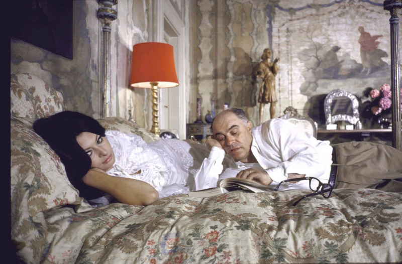 Sophia Loren and husband Carlo Ponti lying across a bed together.