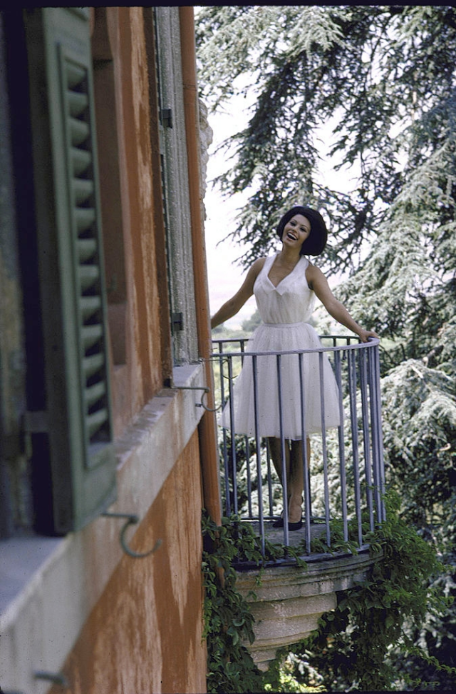 Sophia Loren standing on a balcony at the villa.