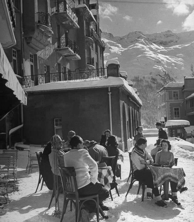 Patons sitting on cafe terrace in snow-covered winter resort.