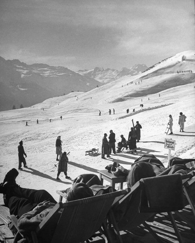 Beginners and avid skiers taking to the slopes, while others are enjoying a lounge chair for watching the activities.