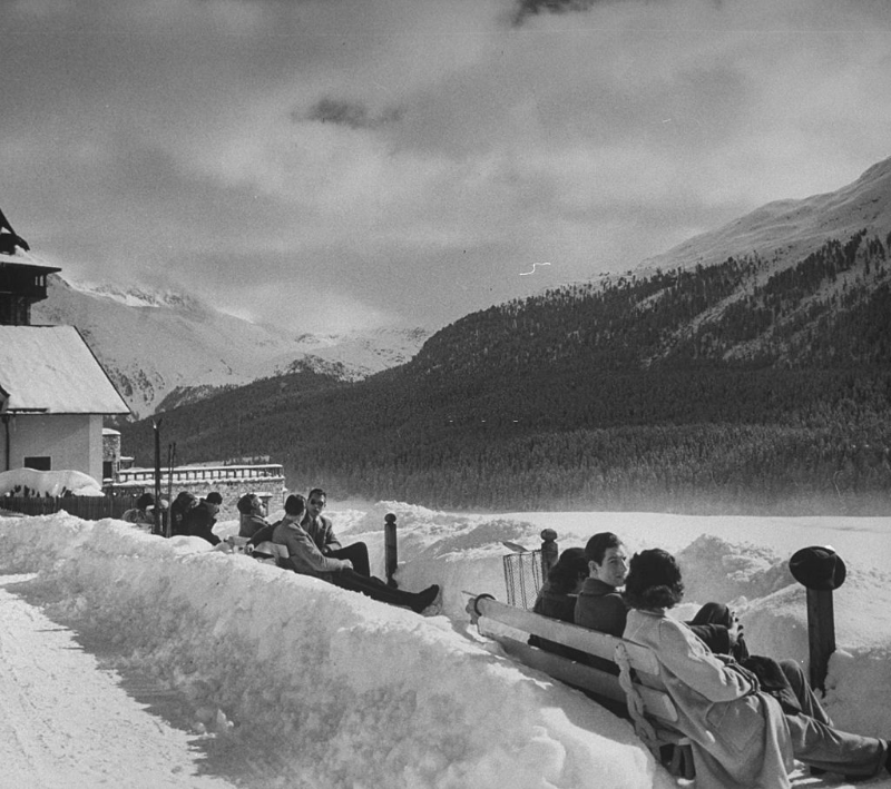 Benches on promenade in center of snow-covered winter-resort village.