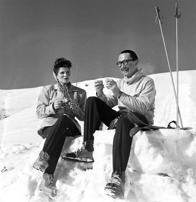 Two skiers chatting on a snow bank in the fashionable winter-resort village of St. Moritz.