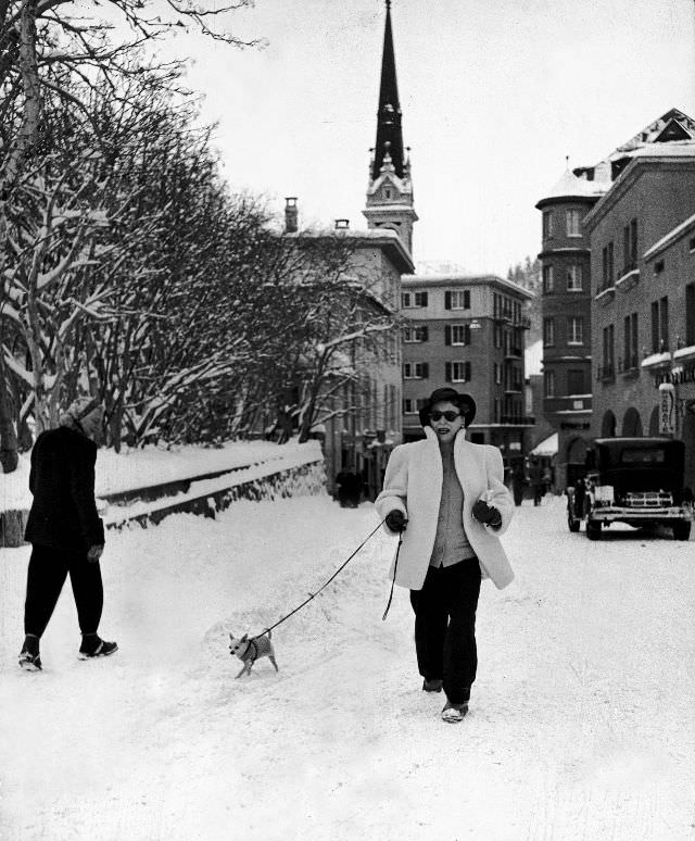 Woman walking pet chihuahua in snow-covered winter-resort village.