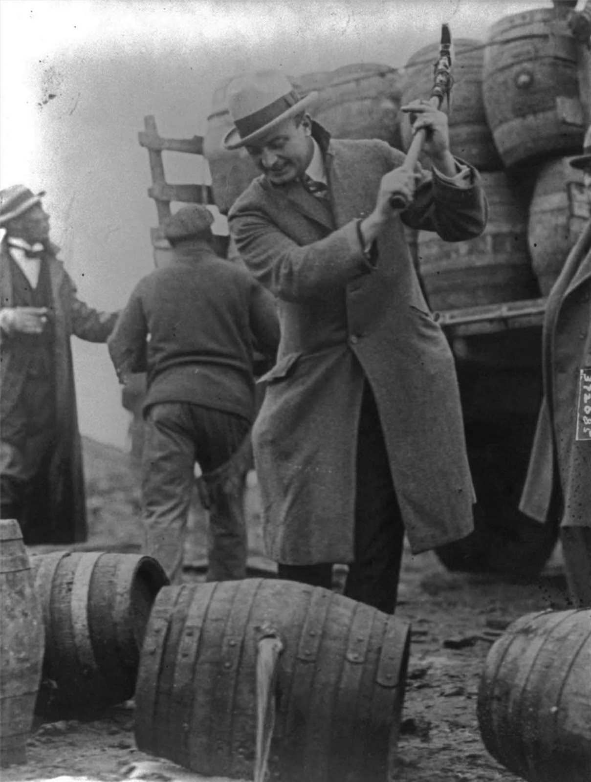 An FBI Officer breaks a confiscated barrel of beer. 1924.