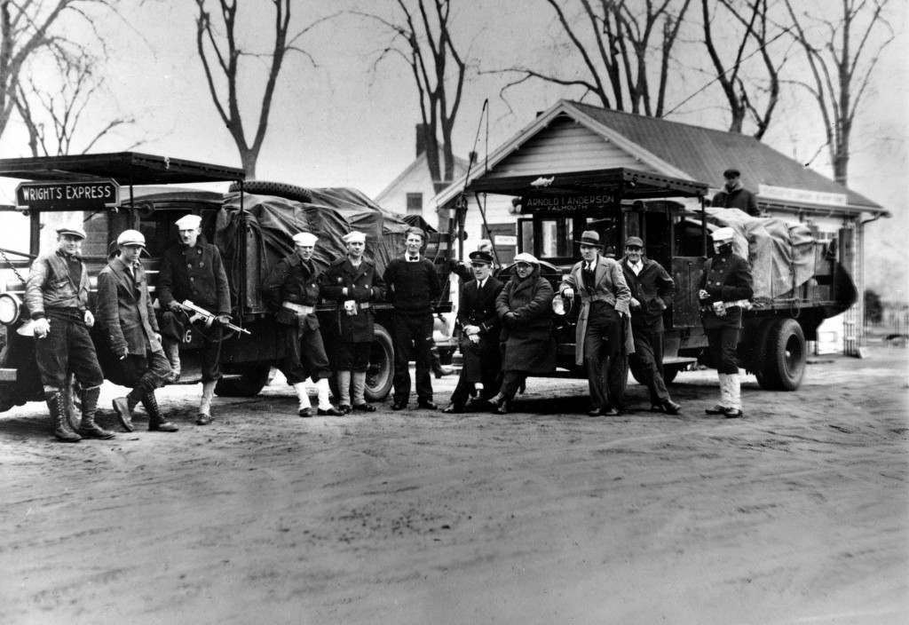 Coast guardsmen stand in front of two truck loads of liquor that were seized after a midnight battle between three Falmouth policemen and a score of alcohol smugglers in the woods near Falmouth, Ma., April 14, 1931. One policeman was injured and all the rum runners escaped.