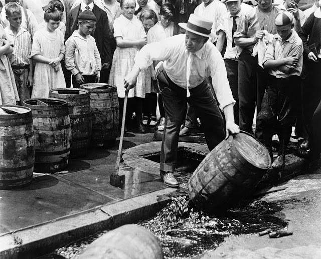 Children watch as a prohibitionist destroys a barrel of beer with an ax during the 1920s.