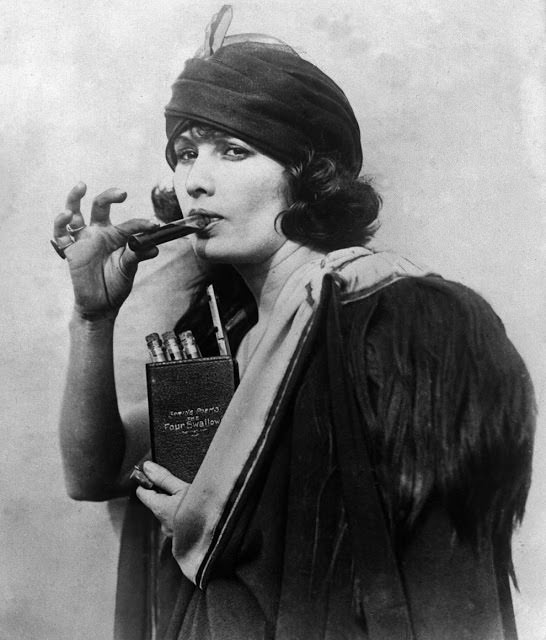 A woman using a dummy book, bearing the title 'The Four Swallows,' as a hiding place for liquor during Prohibition, 1920s.