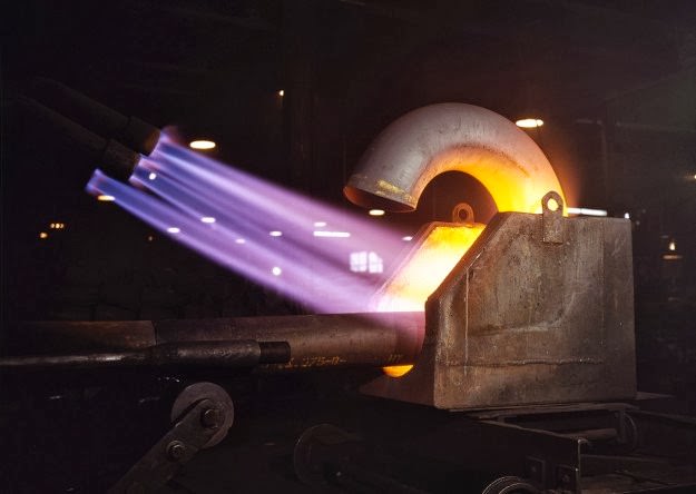 Large pipe elbows for the Army are formed at Tube Turns, Inc., by heating lengths of pipe with gas flames and forcing them around a die, in Louisville, Kentucky, in 1941