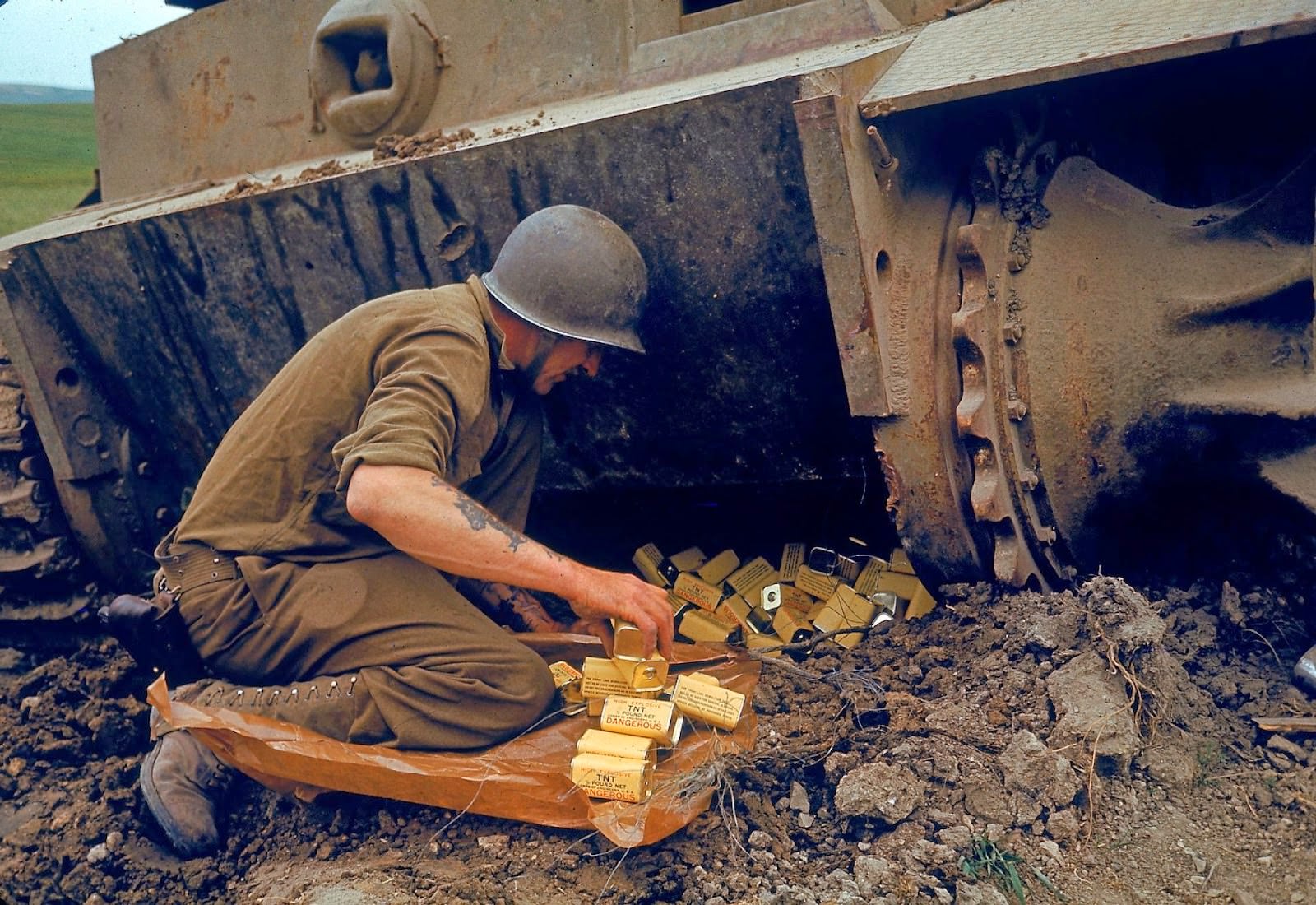 A US Army Corps of Engineers solider packs 1/2 pound tins of the explosive TNT under one end of an abandoned German tank in preparation for detonation during military operations in the El Guettar Valley, Tunisia, early 1943.