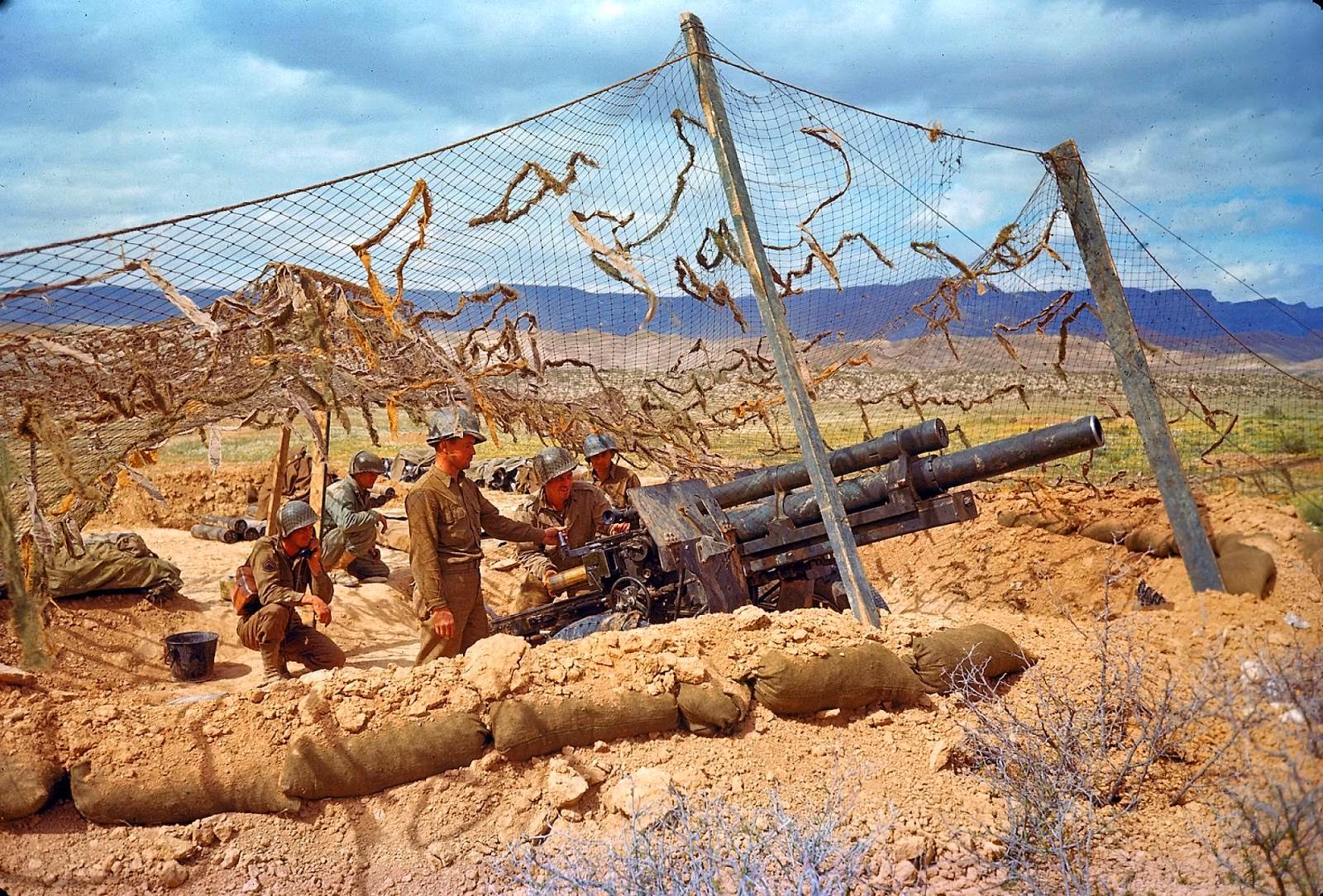 An American gun crew in camouflaged emplacement awaiting orders to fire during the desert fighting between German and American forces in the El Guettar Valley in 1943.