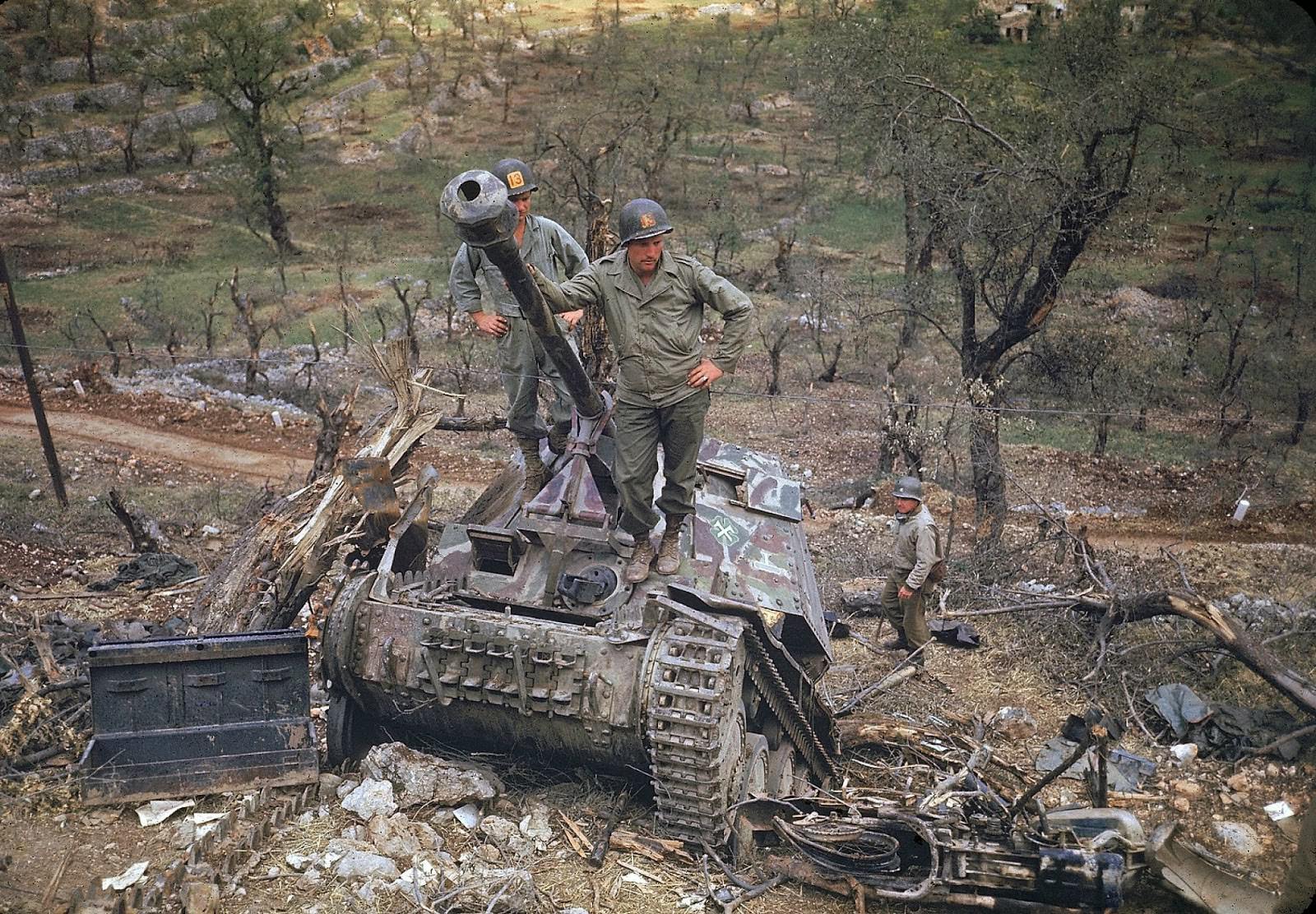 Two soldiers standing on the tank and assessing the destructions.
