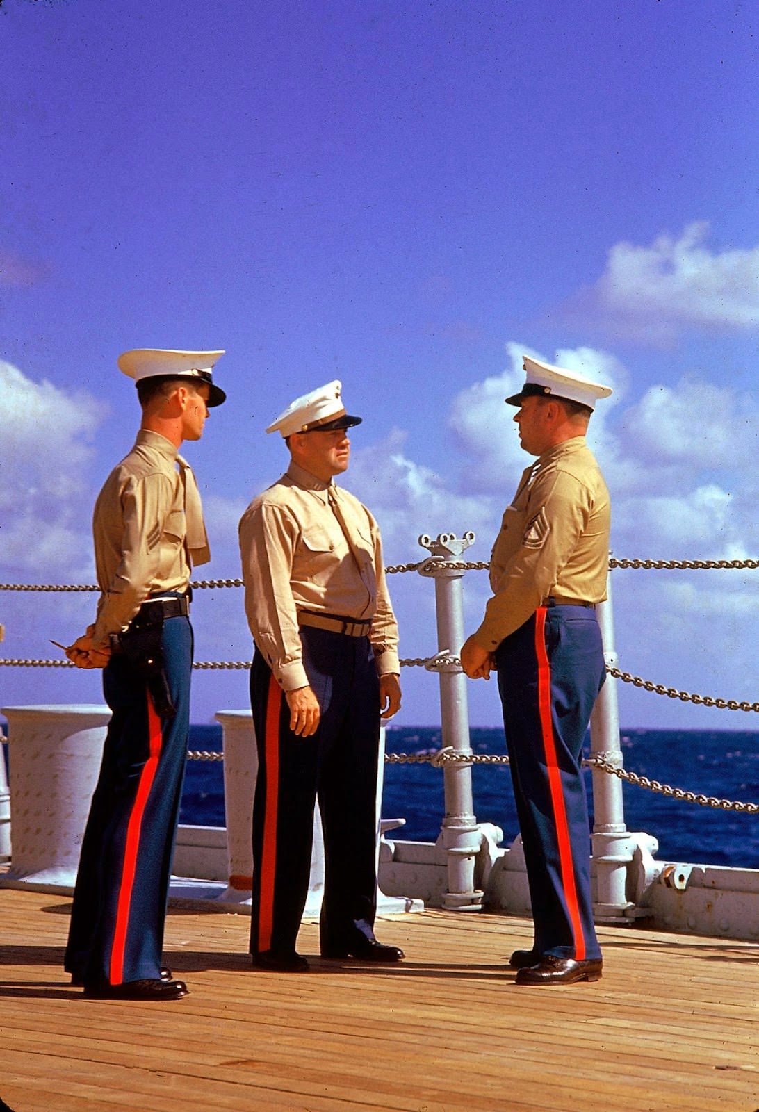 Three American Marines in dress uniforms talk aboard an unidentified ship during the US Navy's Pacific fleet maneuvers near Hawaii, September 1940.