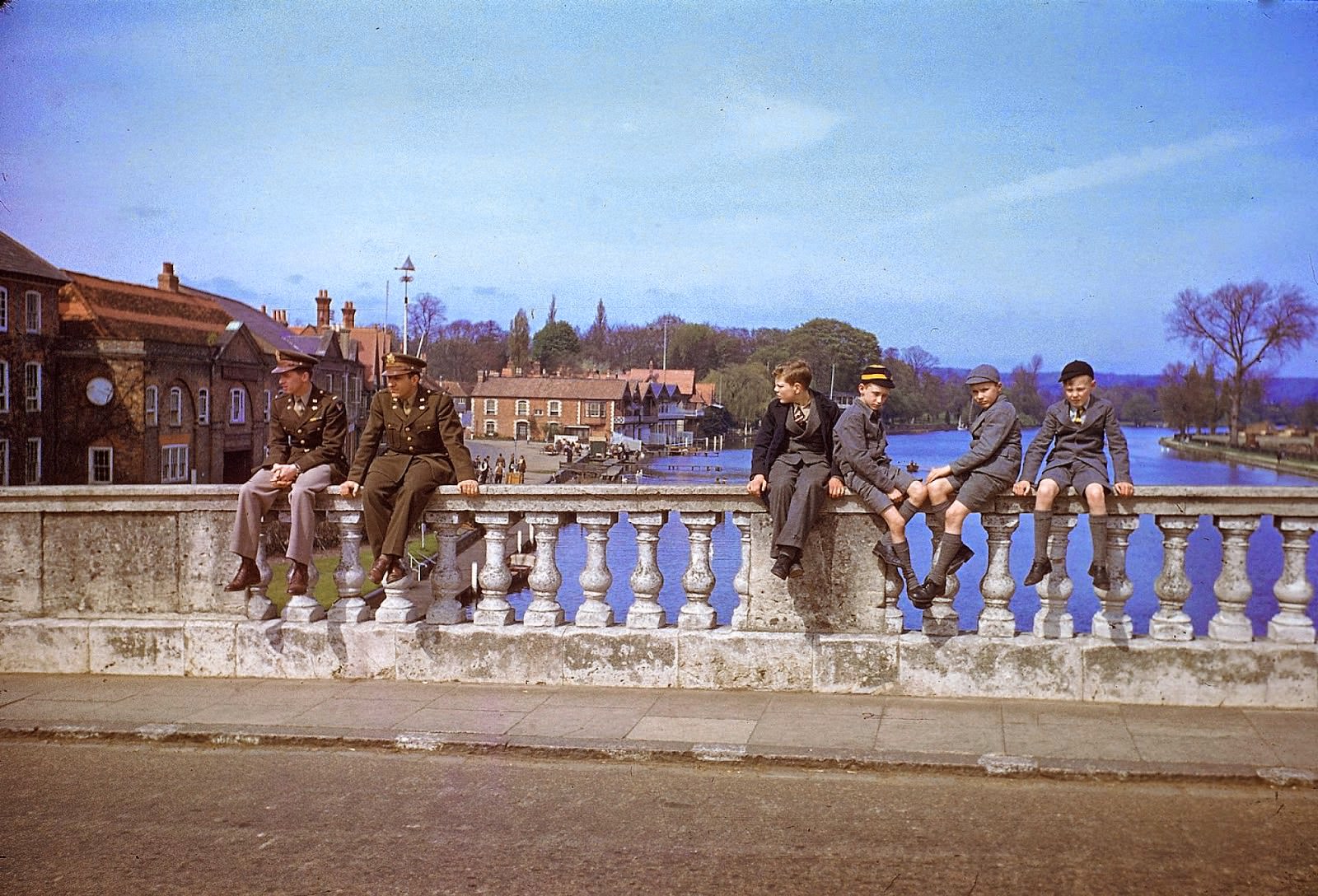 A pair of servicemen and a quartet of schoolboys sit on bridge over the Thames, Henley-on-Thames, England, May 1944.