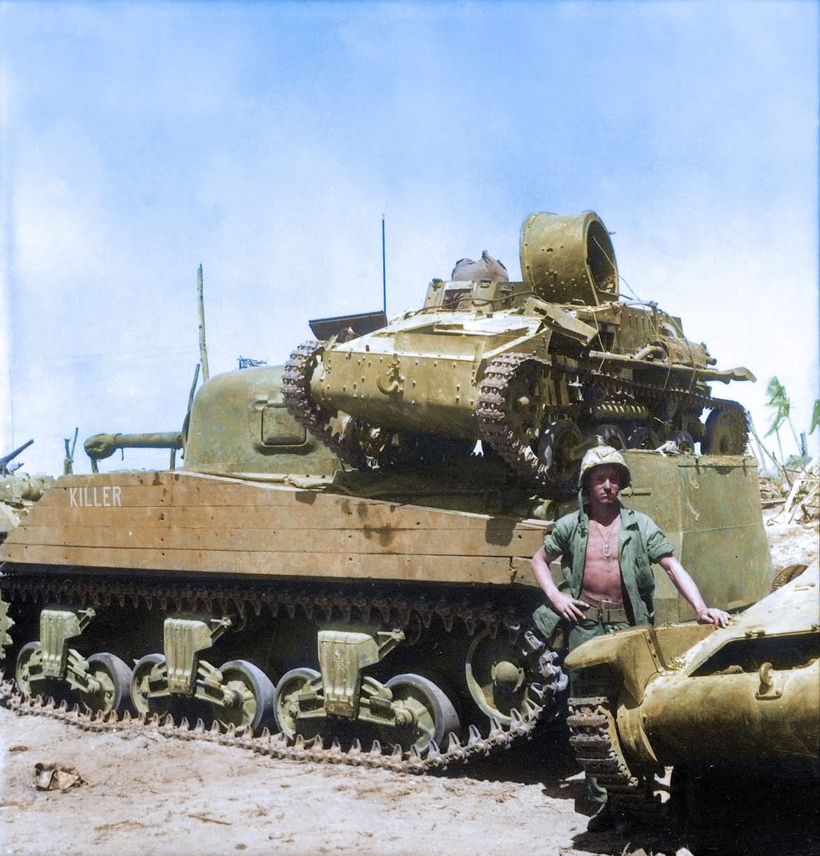 Private First Class N. E. Carling stands beside the American M4 Sherman medium tank 'Killer' on Kwajalein Atoll.