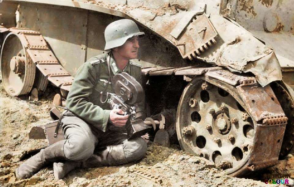 A Kriegsberichter (war correspondent) holding an Arriflex 35 2 1942 camera 35mm ACR 0292 and he is leaning against a knocked out Soviet BT-5 light tank. c.1940/41