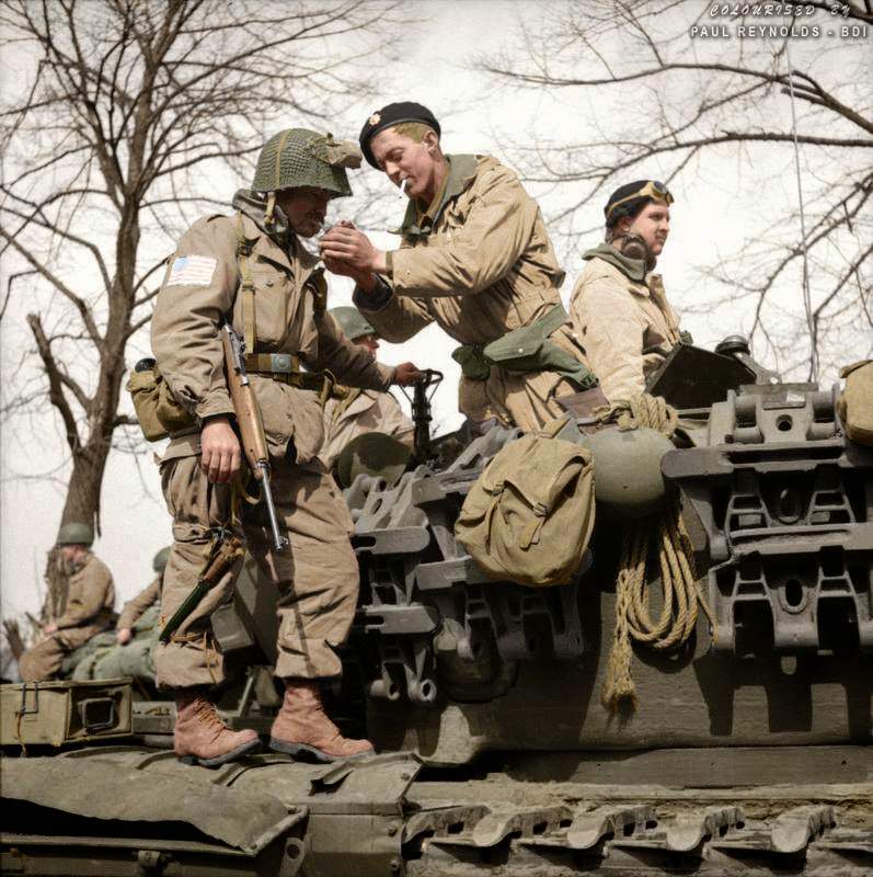 A paratrooper from the American 17th Airborne Division gets a light from a Churchill tank crewman of 6th Guards Armoured Brigade near Dorsten in North Rhine-Westphalia, Germany, 29th of March 1945.