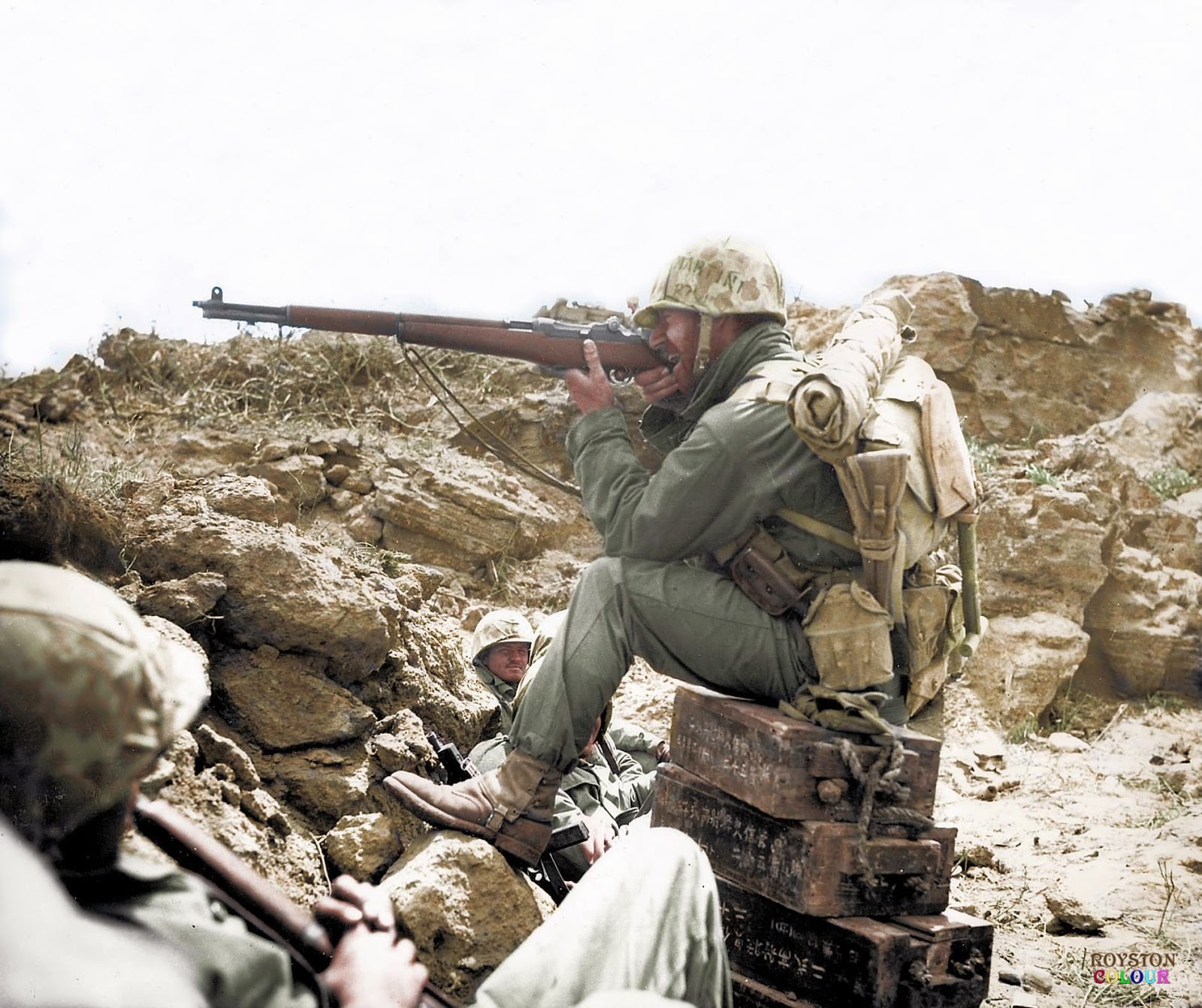 An American Marine aiming his Garand M1 rifle, whilst perched on Japanese ammunition crates on the Island of Iwo Jima, c. February/March 1945