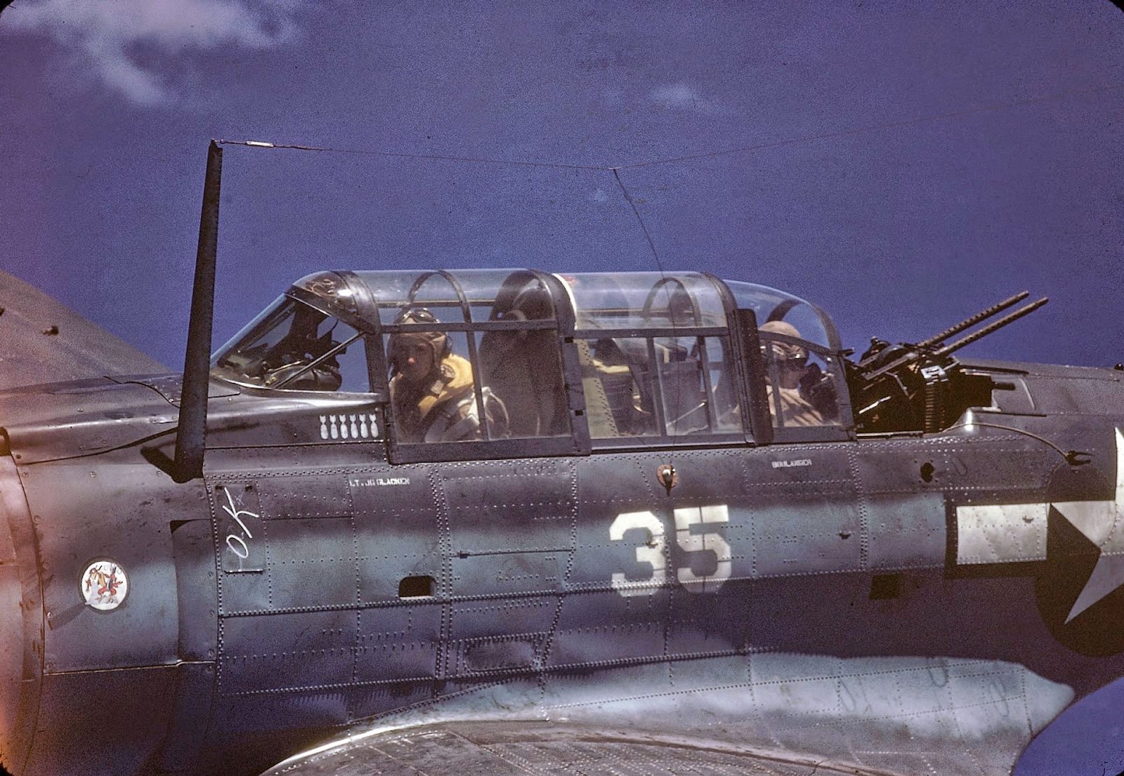 Close-up, in-flight view of a Douglas SBD Dauntless piloted by American Lt. George Glacken (left) with his gunner Leo Boulanger, near New Guinea, early April, 1944.