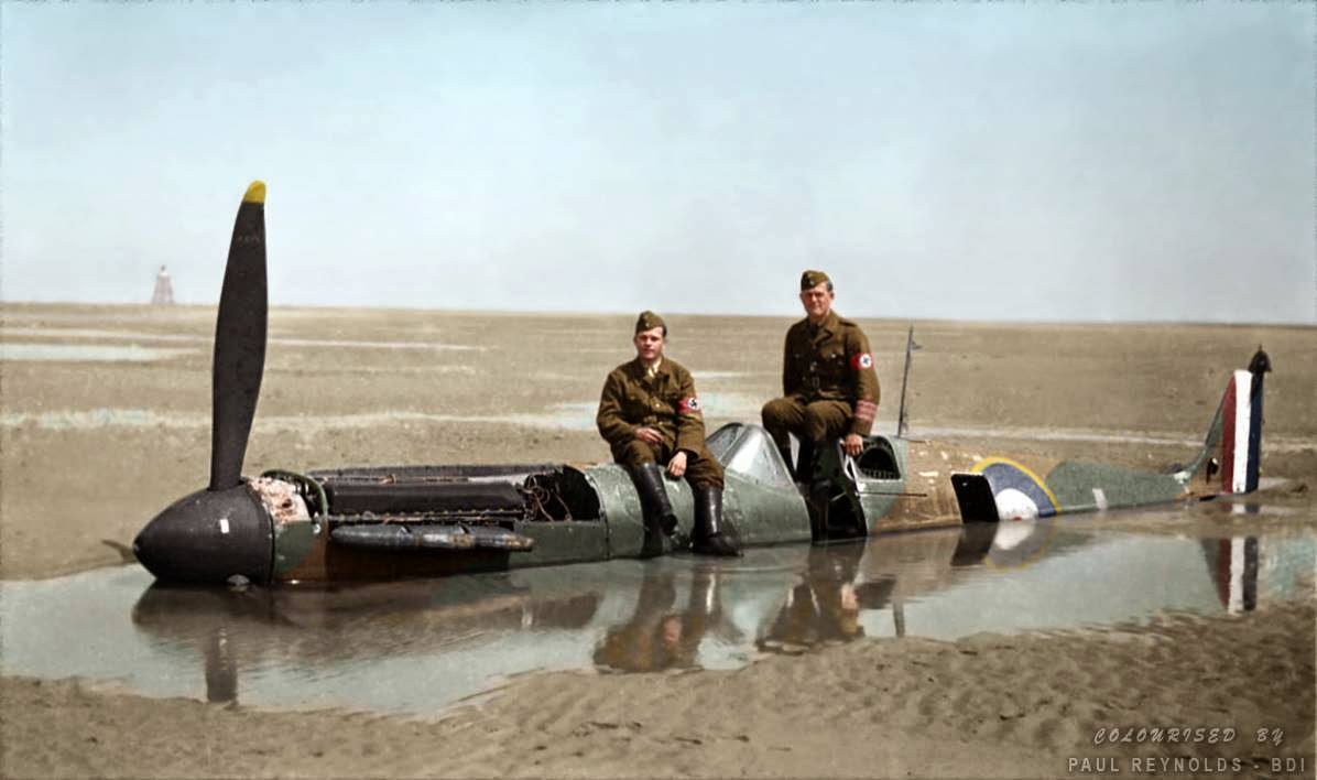 Two German members of the Organisation Todt (involved in the construction of the Atlantic Wall) are sitting on the Spitfire brought down on the wet sands at Calais by Flying Officer Peter Cazenove.