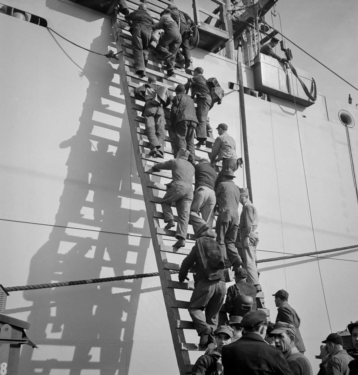 Workers climb a ladder on the outfitting pier