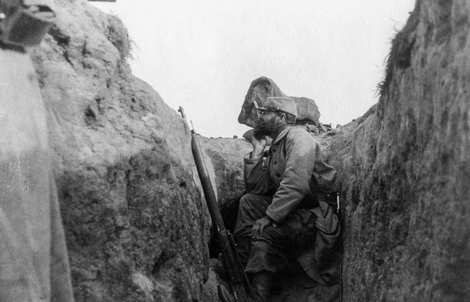 A French soldier peers over the edge of a trench.