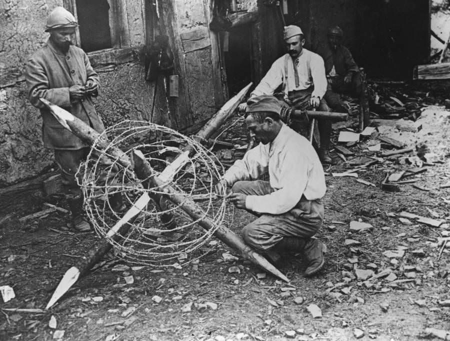 A man builds barbed wire defenses.