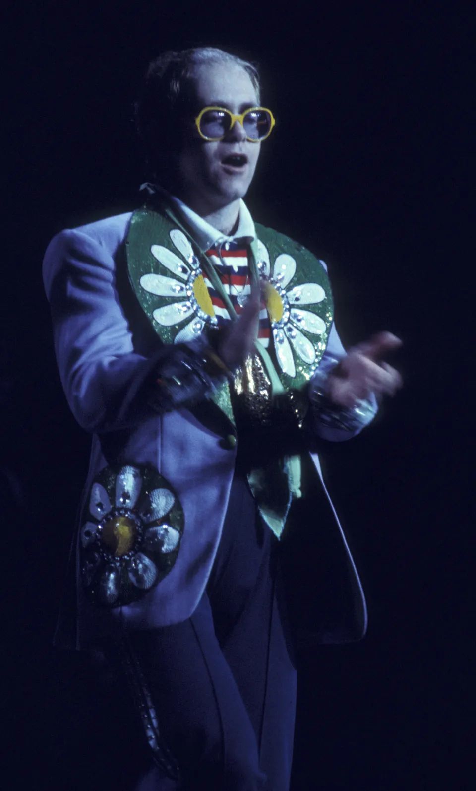 Elton John wearing a suit emblazoned with named stars, 1975