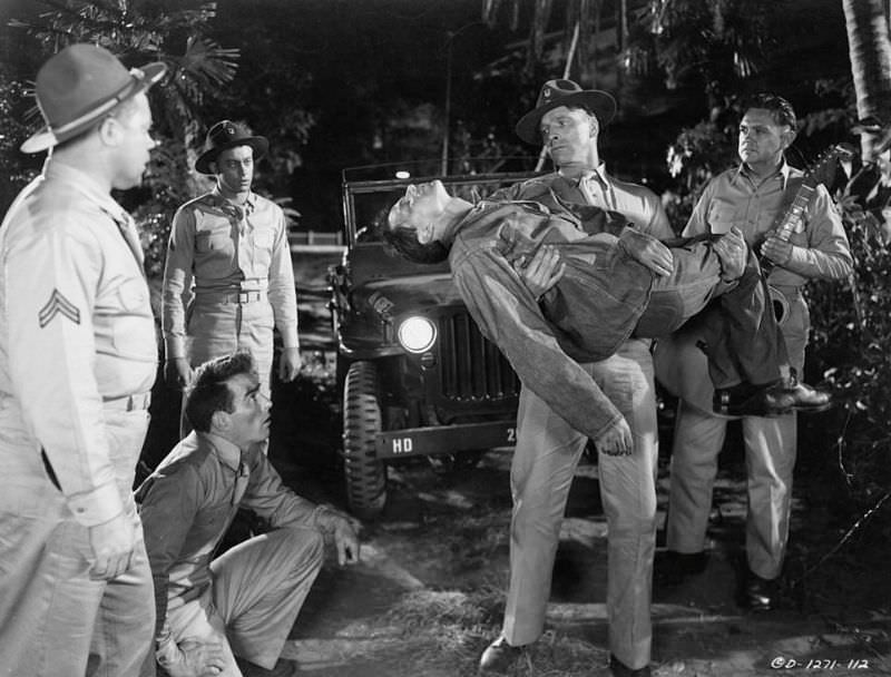 Montgomery Clift looking up as Burt Lancaster carries fellow fallen man in a scene from the film 'From Here to Eternity,' 1953.