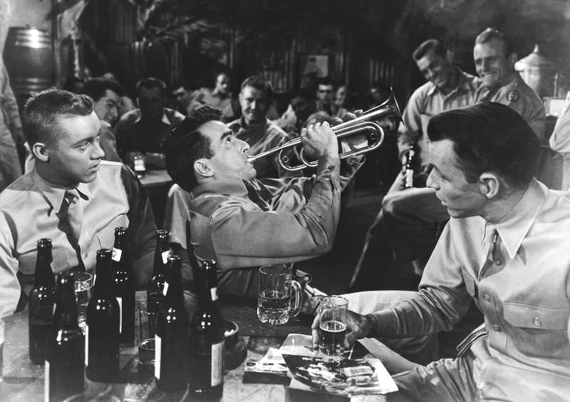 Montgomery Clift plays the trumpet while Frank Sinatra watches in a scene from the film 'From Here to Eternity,' 1953.