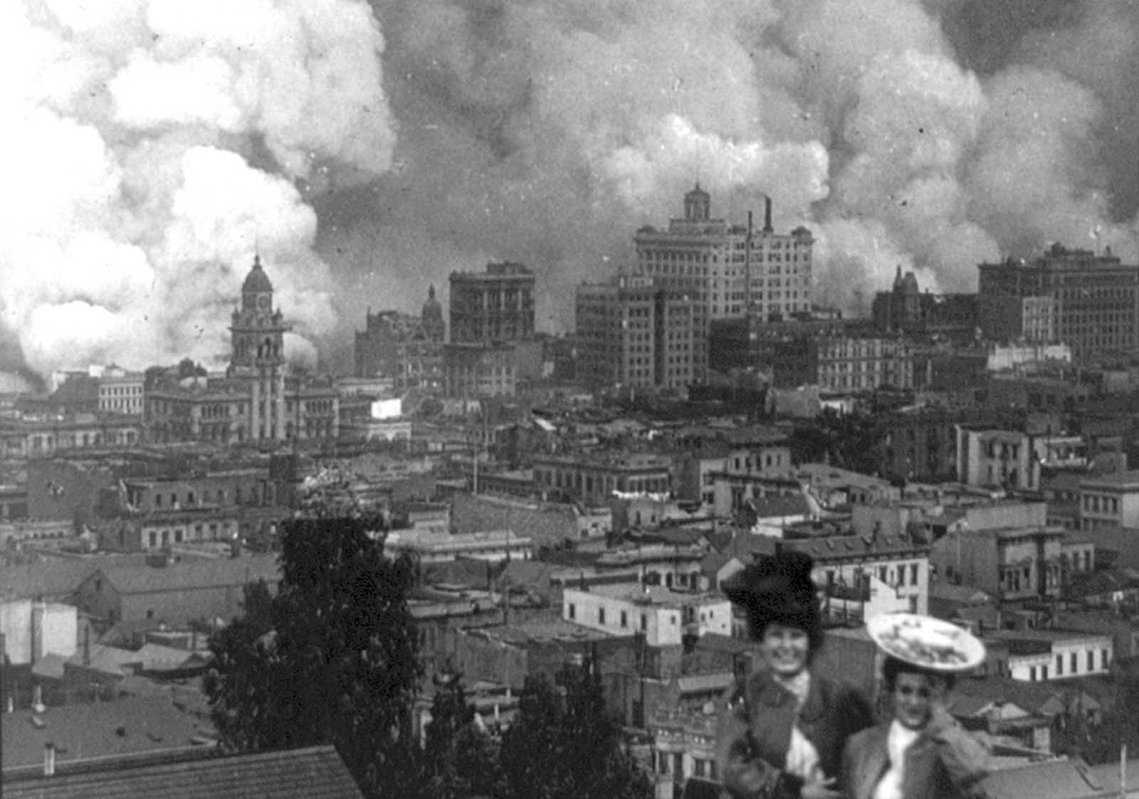 Onlookers pose for a photograph as San Francisco burns in the background on April 18, 1906.