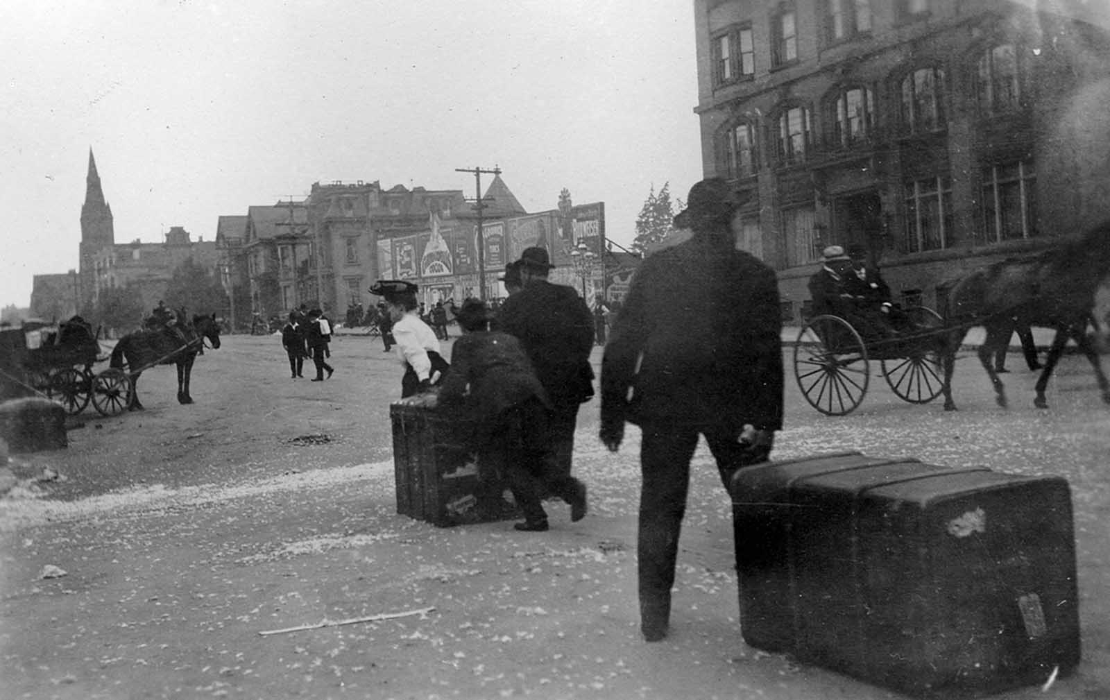 Evacuees drag trunks from the fire on Van Ness Avenue.