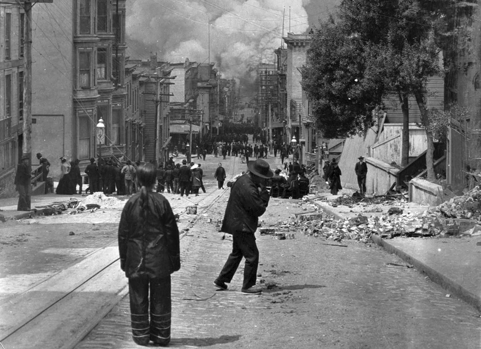 San Francisco residents stand in the rubble-strewn streets watching the fire grow after the earthquake struck on April 18, 1906.