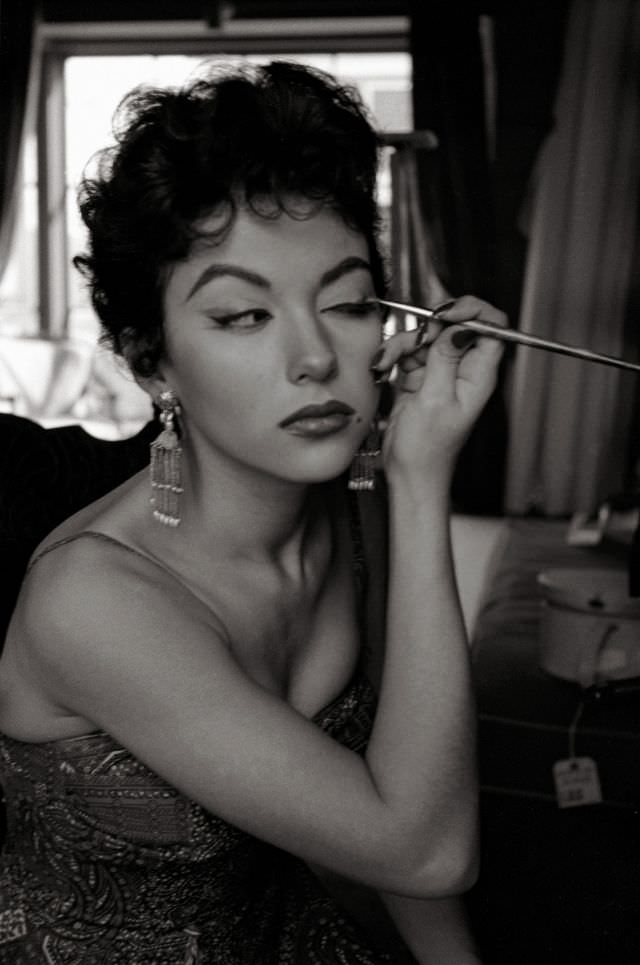 Rita Moreno applies make-up in a mirror, Hollywood, California, 1954.