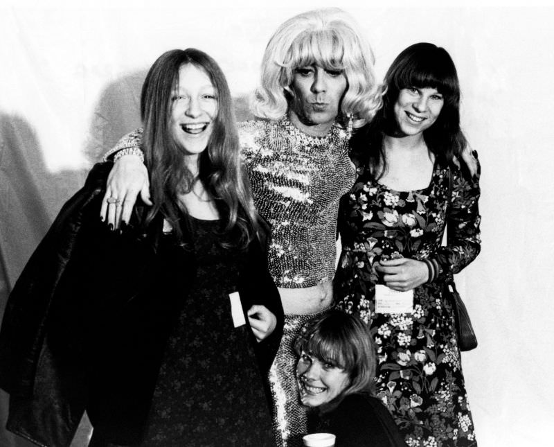 The Who drummer, Keith Moon, poses with fans while dressed in a blonde wig and sequin outfit backstage at a concert in 1972