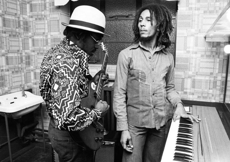 Aston 'Family Man' Barrett and Bob Marley of The Wailers playing guitar and keyboards backstage at the Odeon, Birmingham, United Kingdom, July 18, 1975