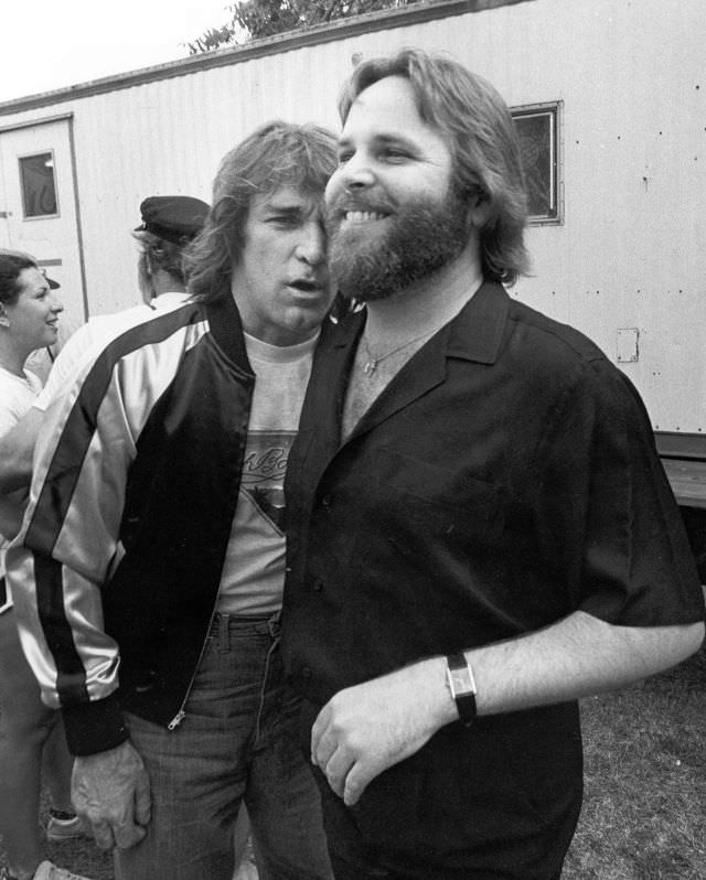 Dennis Wilson and Carl Wilson of The Beach Boys hang out after an outdoor concert in 1975