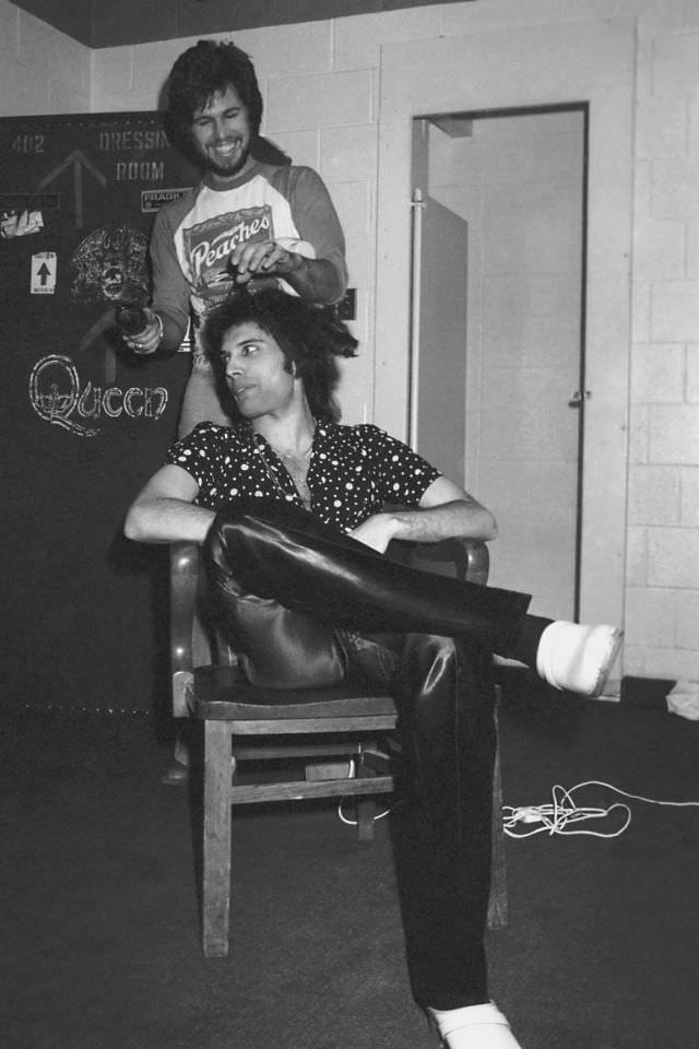 Freddie Mercury gets his hair done backstage, before a concert, circa 1977